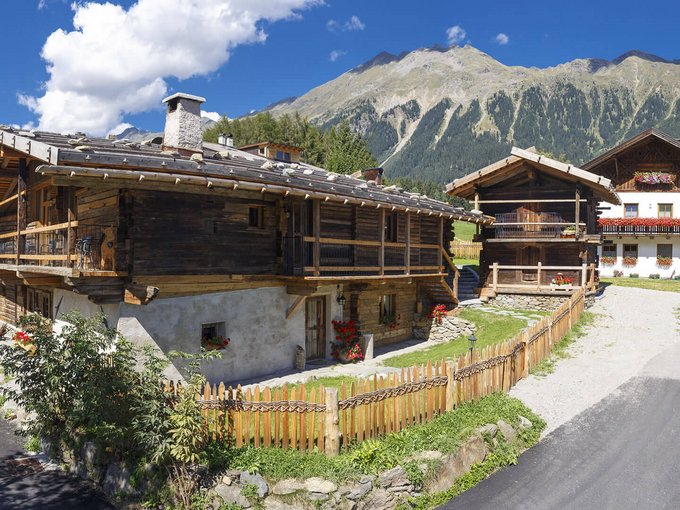 Vacanze sostenibili Case di montagna e fattoria in villaggio con montagne sullo sfondo sotto il sole