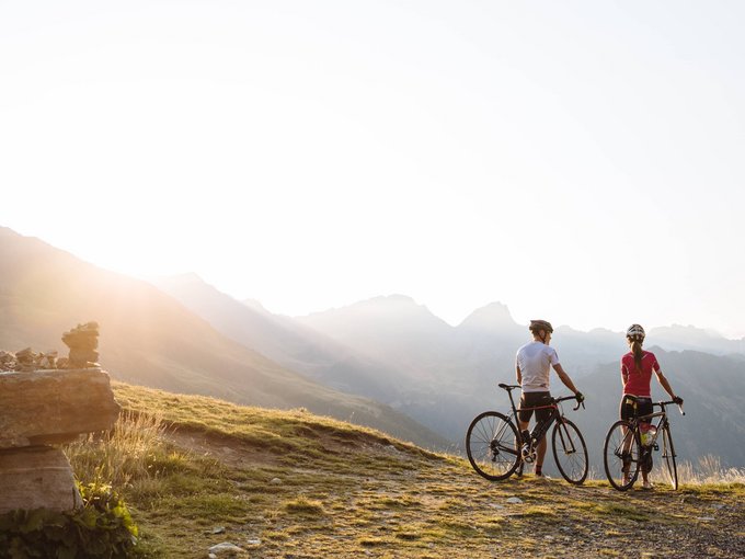 Tour in bici Due ciclisti con biciclette da corsa su un sentiero di montagna al tramonto