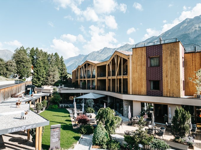 Inclusive services Modern hotel with wooden facade and terrace against mountain backdrop
