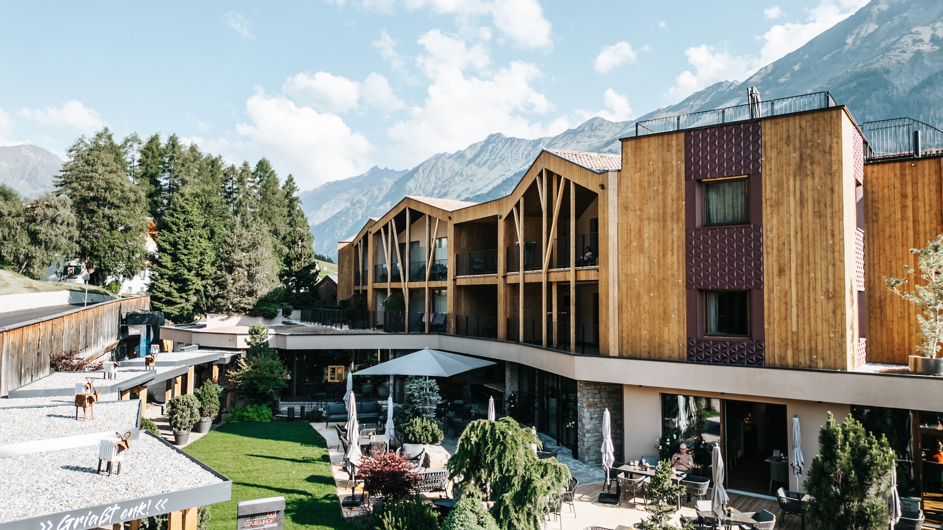 New at Gassenhof Modern hotel with wooden facade and terrace against mountain backdrop