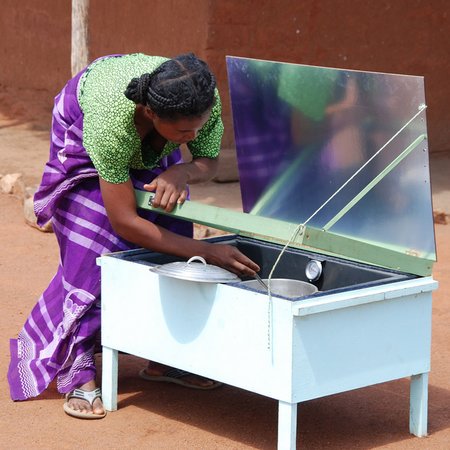 Neuigkeiten Frau bedient einen Solarkocher im Freien