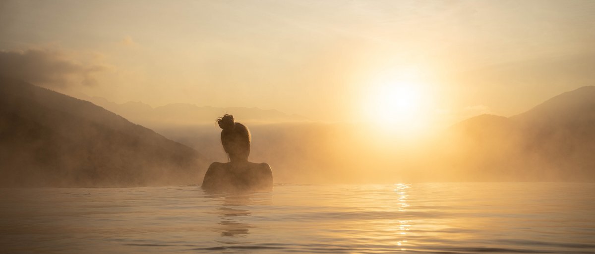 Das Logen-Spa Person entspannt im warmen Wasser bei Sonnenaufgang in den Bergen