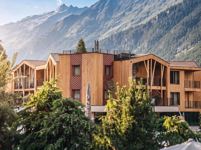 Servizi inclusi Edificio in legno davanti a un'imponente montagna, circondato da abeti