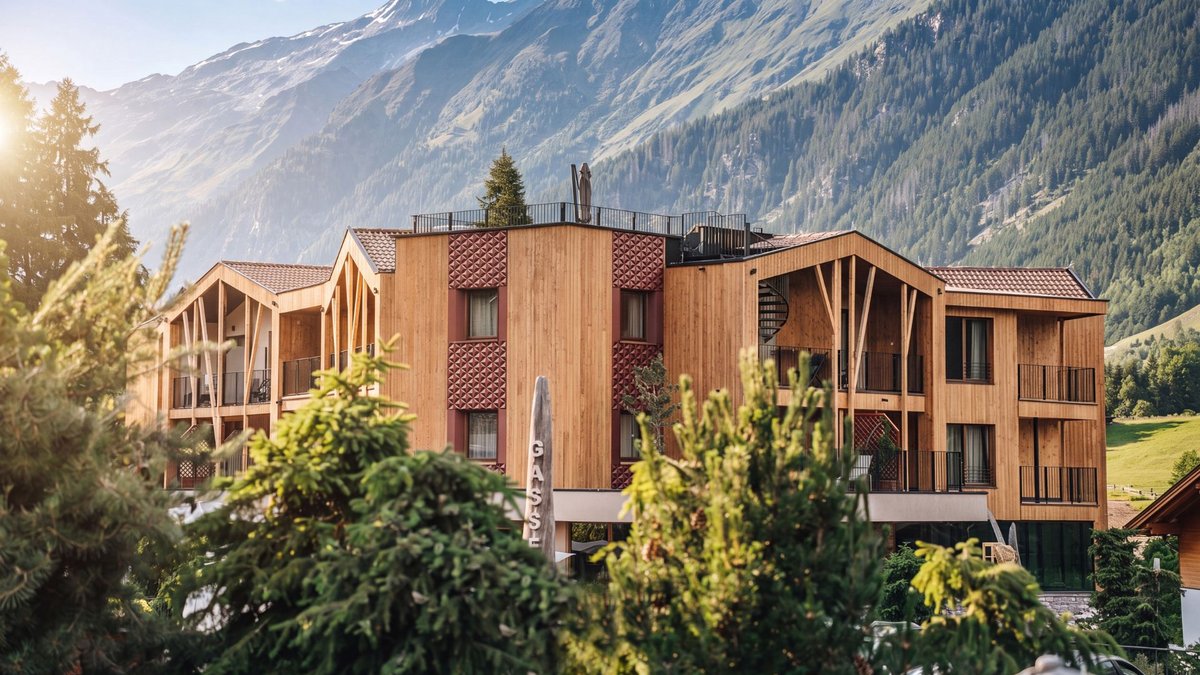 Familienurlaub im Gassenhof Holzgebäude vor einer beeindruckenden Berglandschaft, umgeben von Tannen