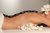 Frau bei Hot Stone Massage mit weißen Blumen im Spa