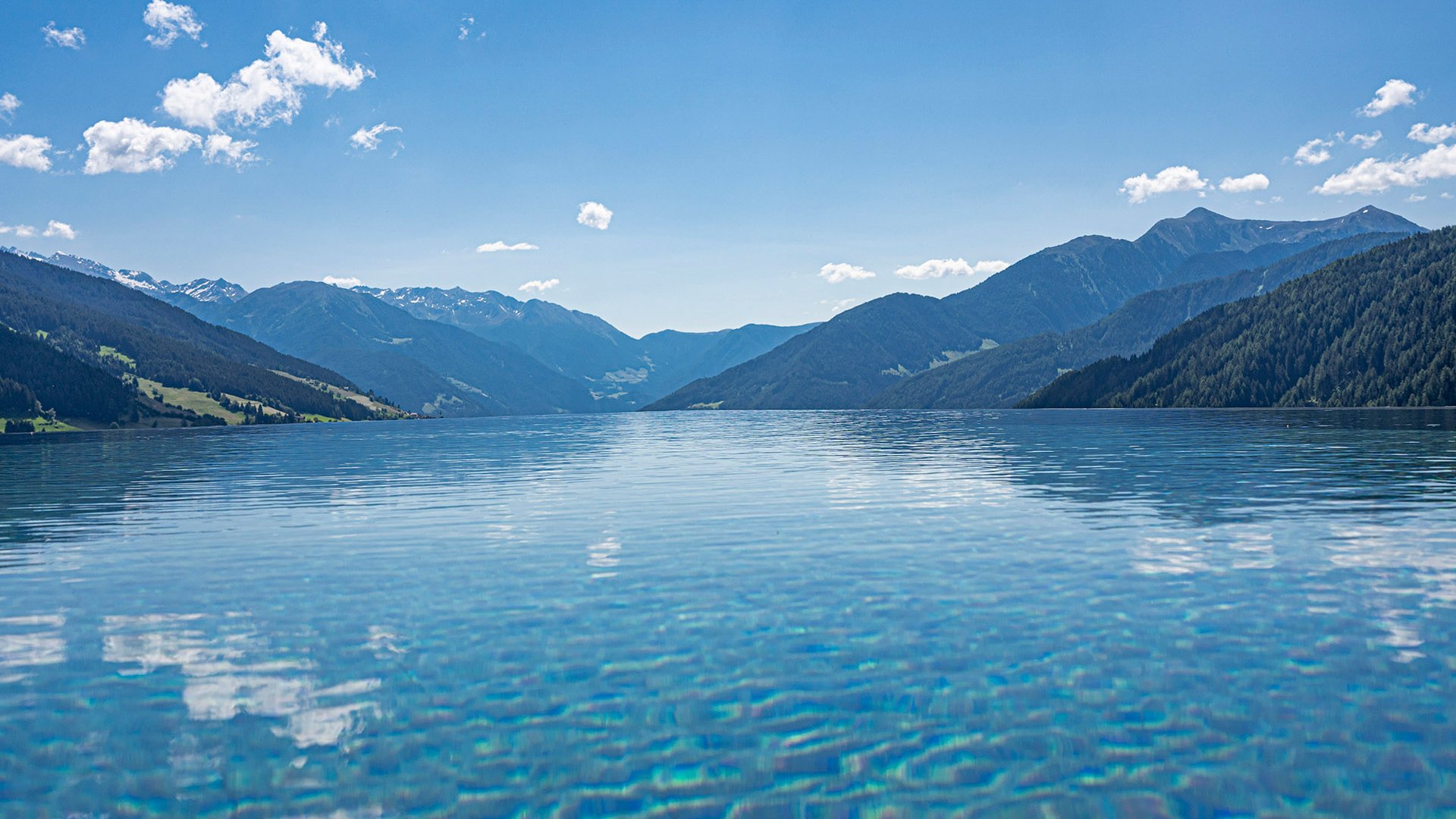 Die Wasserwelt Klares Wasser eines Sees umgeben von Bergen unter blauem Himmel