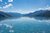 Klares Wasser eines Sees umgeben von Bergen unter blauem Himmel