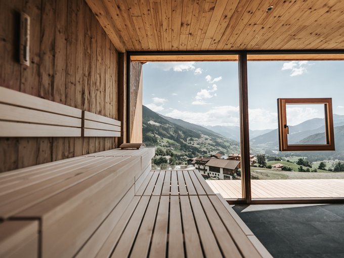 Das Wellnessbereich für Erwachsene Holzsauna mit Panoramafenster und Blick auf Berge und Tal