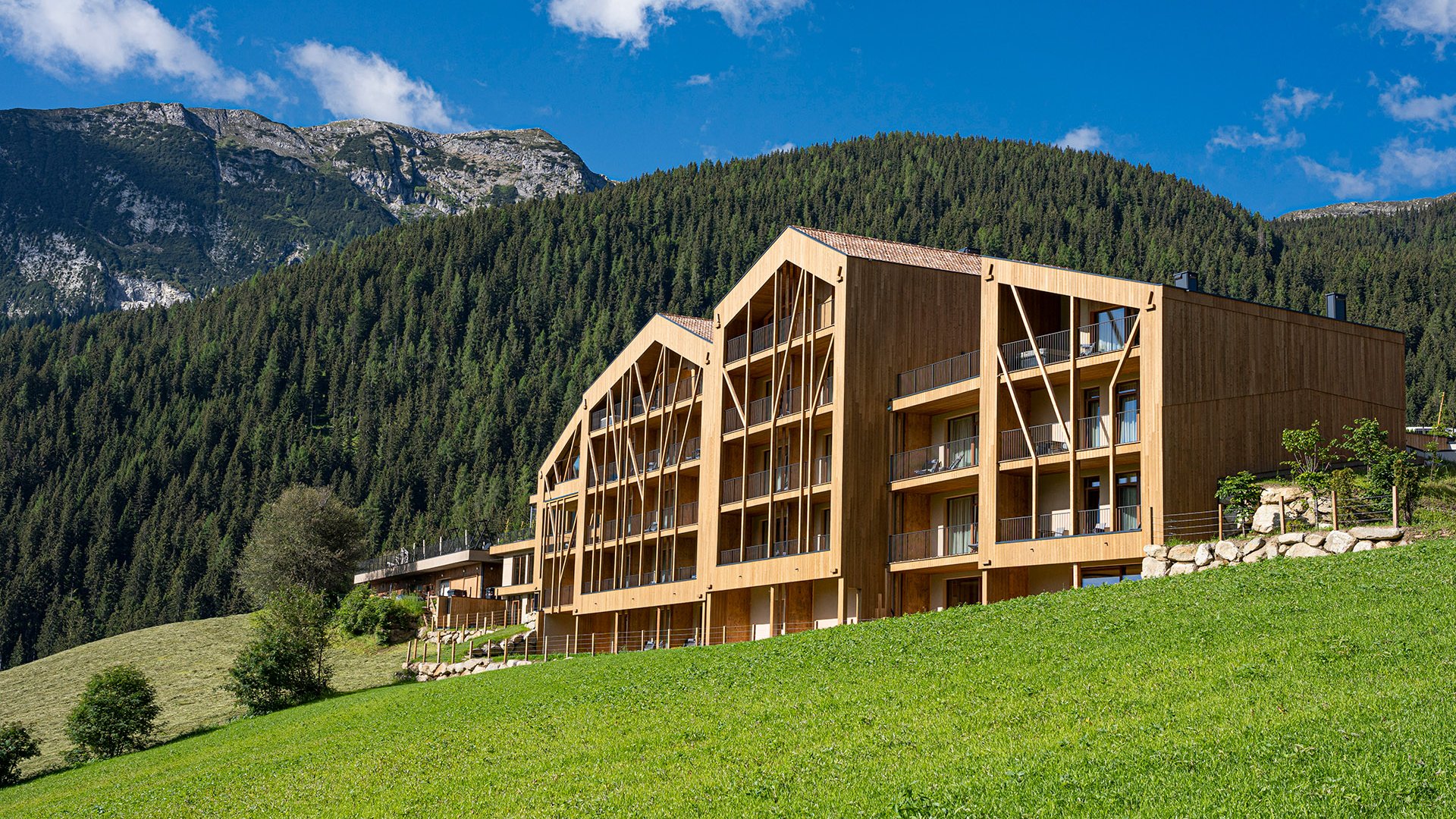 The best spot in the Ridnauntal valley Modern wooden building with forested mountain and blue sky background