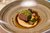 Gourmetgericht mit Kräuterkruste, Cremesoße und Gemüse auf Teller angerichtet