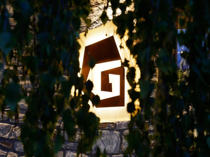 Inclusive services Illuminated square metal logo on stone wall behind leaves