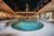 Galleria immagini Elegante piscina interna con aree relax, soffitto in legno e lampadario