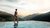Frau im Infinity-Pool mit Blick auf Berglandschaft bei Sonnenuntergang