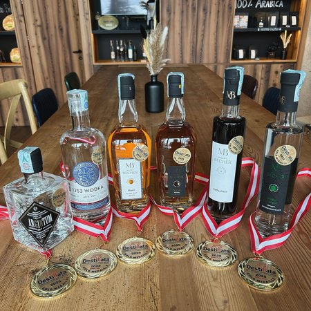 Neuigkeiten Mehrere prämiere Spirituosenflaschen mit Goldmedaillen auf Holztisch