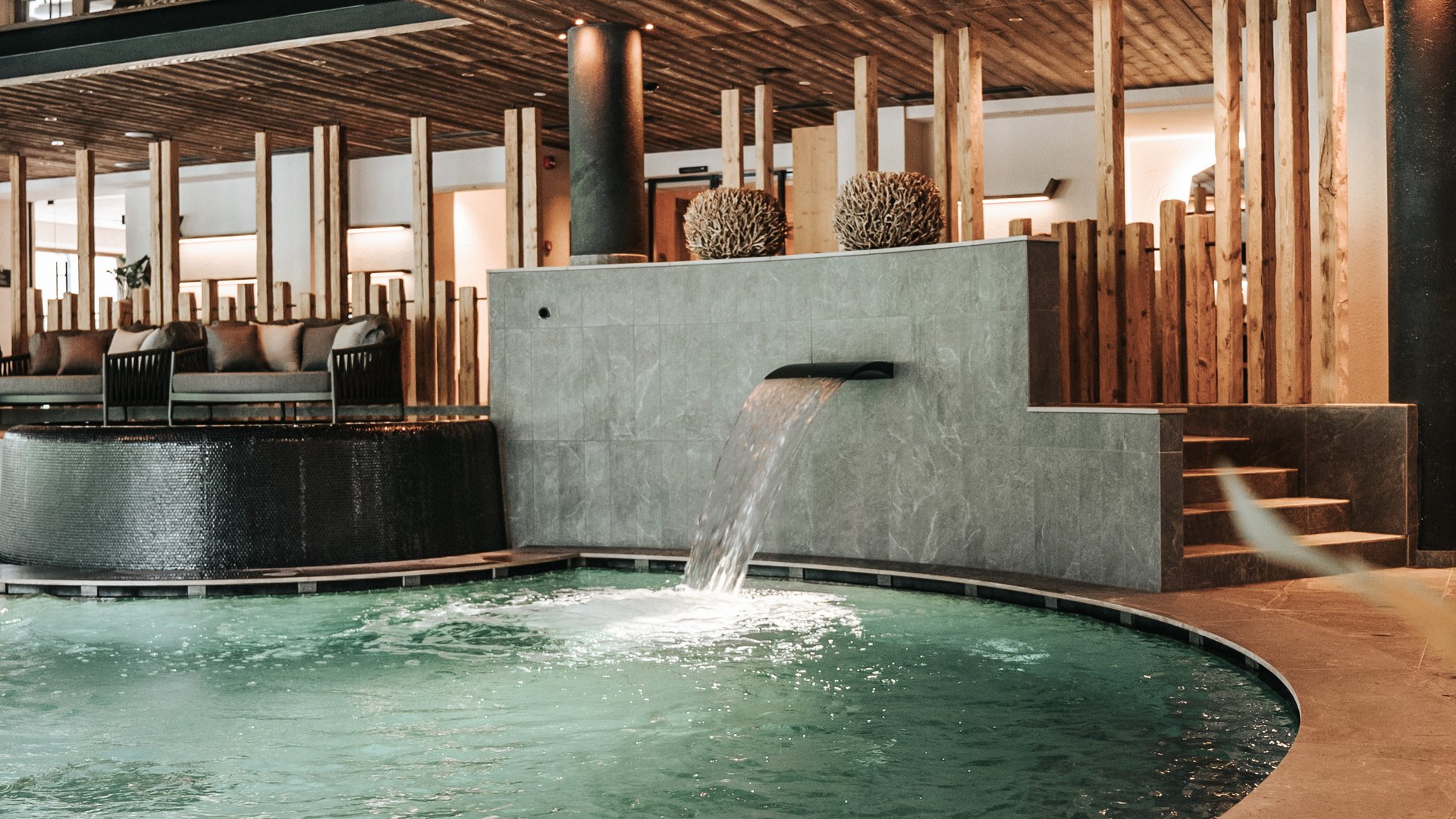 Our water world Indoor pool with waterfall and wooden ceiling in a luxurious spa area