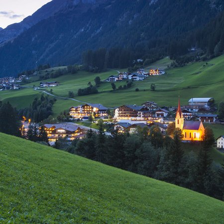 La Val Ridanna Piccolo villaggio alpino al tramonto con chiesa illuminata e prati verdi