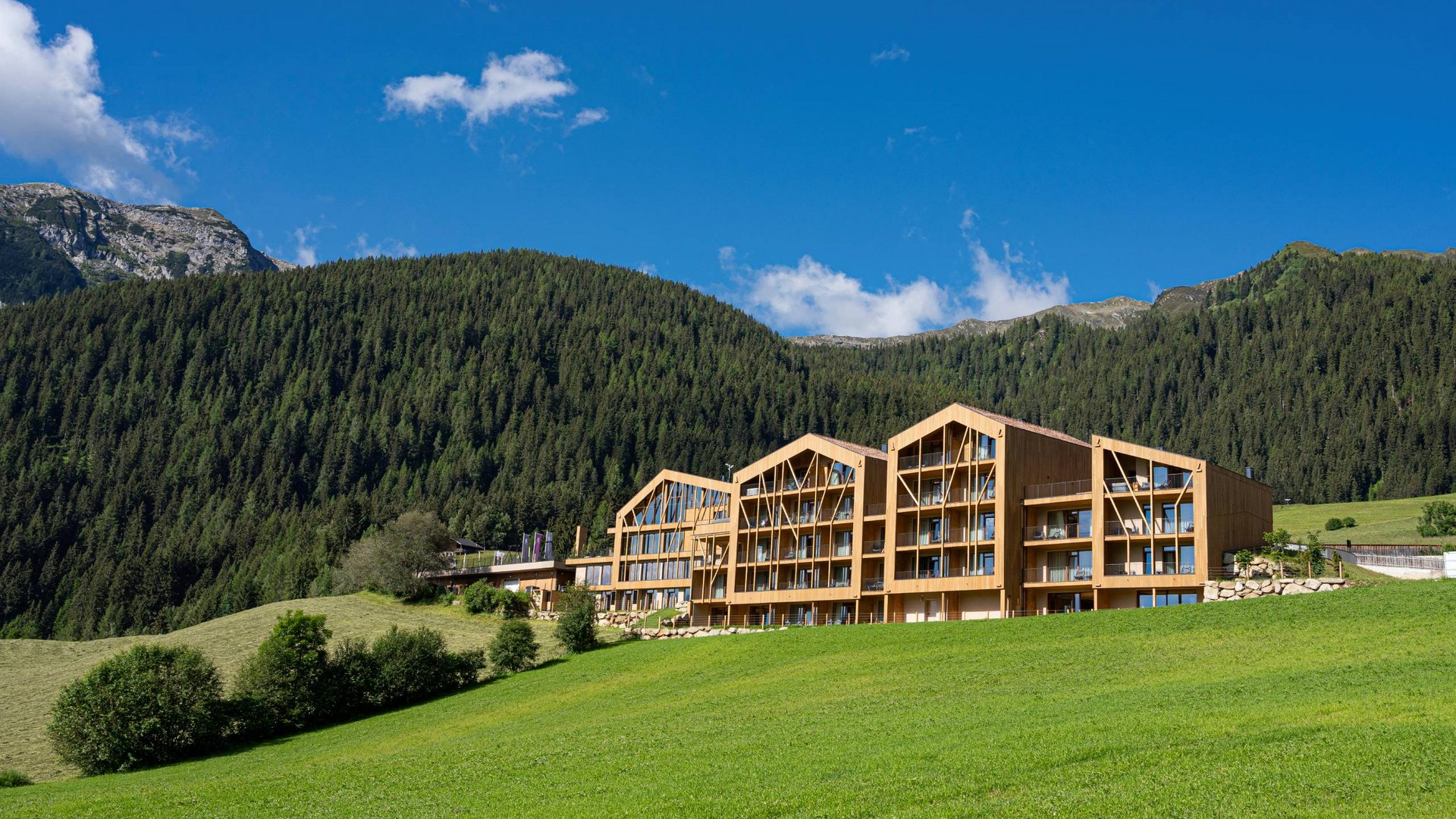 Modern wooden building with forested mountain and clear blue sky