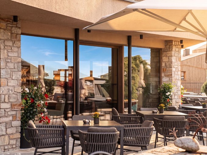 A place of experiences Covered restaurant terrace with tables, wicker chairs and flowers