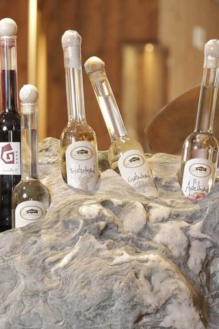 Home Erlebnisort Gassenhof Various schnapps bottles displayed in a large stone holder in a warm setting