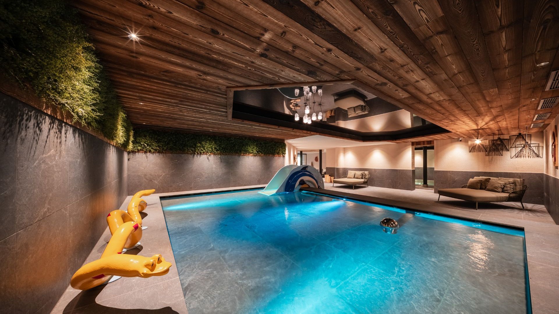Gassenbadl: l’area wellness per famiglie Piscina interna con soffitto in legno, lettini e coccodrillo gonfiabile giallo