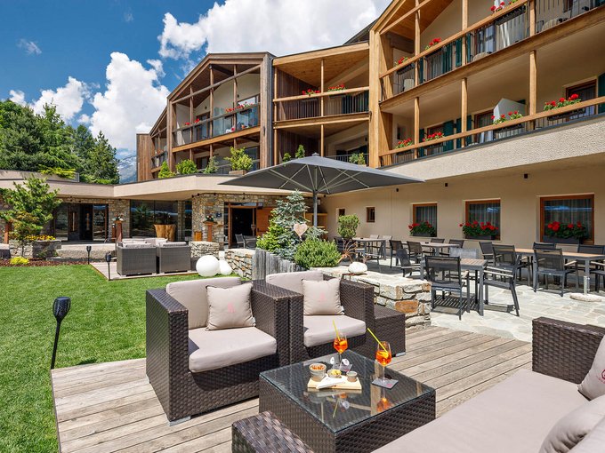 Der Erlebnisort Gassenhof Moderner Außenbereich eines Hotels mit Sitzbereichen und Sonnenschirm bei Sonnenschein