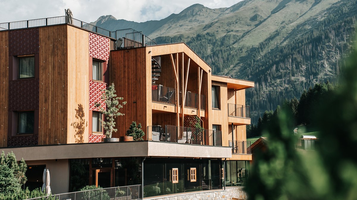 New at Gassenhof Modern wooden building with balconies against mountain landscape on clear day