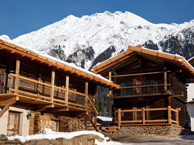 Vacanze sostenibili Baite di legno davanti a montagna innevata in inverno soleggiato