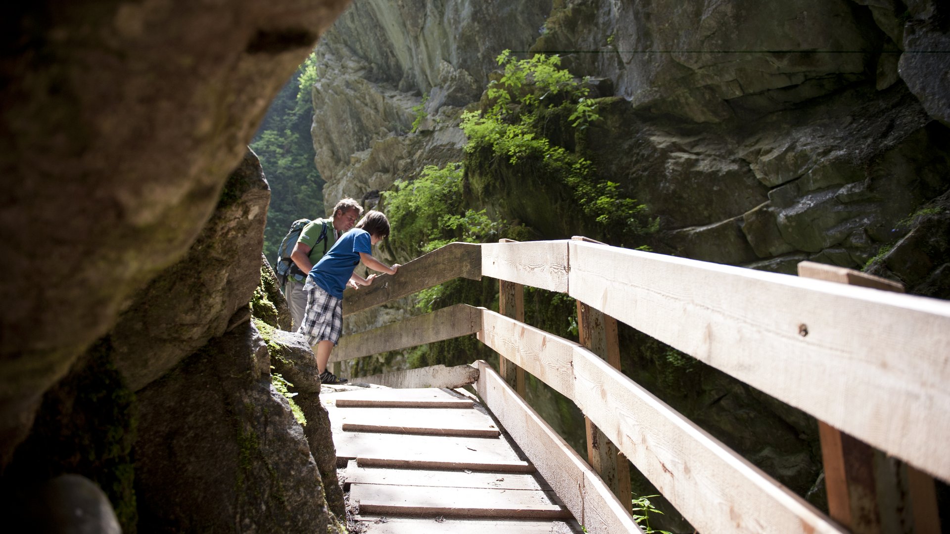 activeCARD Padre e figlio camminano su un ponticello in legno tra le rocce