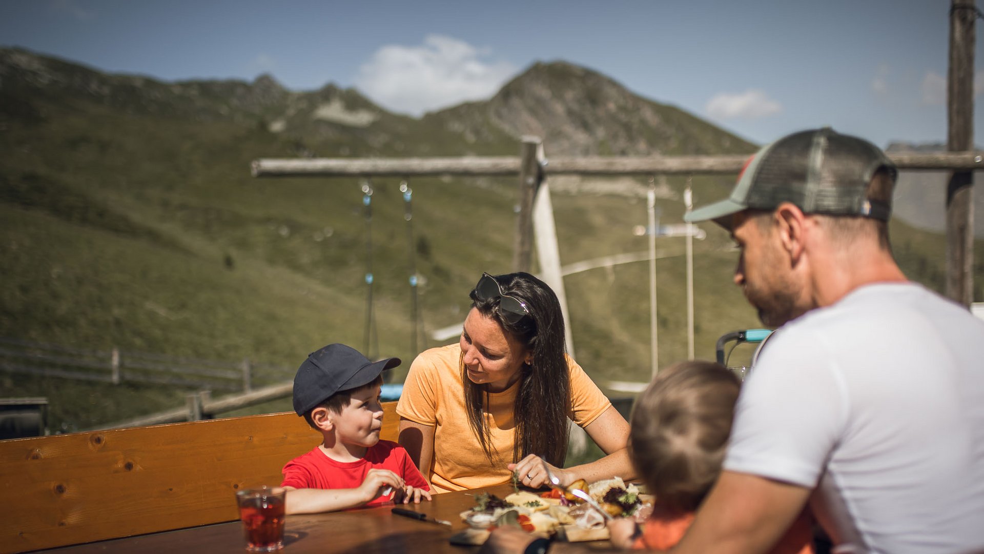 Familienurlaub im Gassenhof Familie beim Essen auf einer Terrasse vor einer Bergkulisse