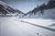 Zwei Skifahrer auf Loipe in verschneitem Bergtal bei Sonnenschein