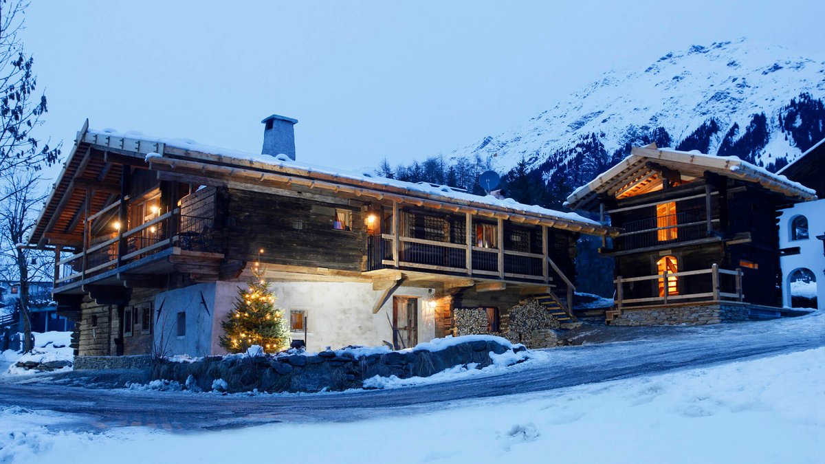 The historical Chalet Gratznhäusl Cozy mountain cabin in snow with lit Christmas tree in the evening
