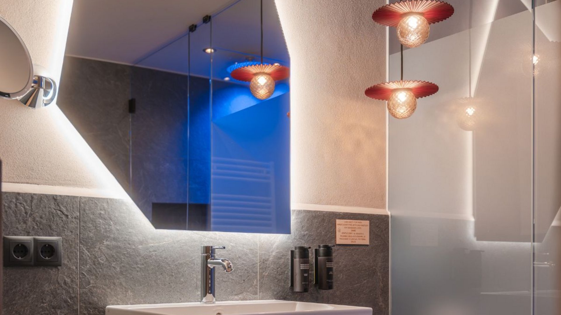 Zimmer und Suiten Modernes Badezimmer mit Waschbecken, großem Spiegel und dekorativen Pendelleuchten