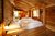 Gemütliches Holzschlafzimmer mit weißer Bettwäsche und Badewanne im Hintergrund