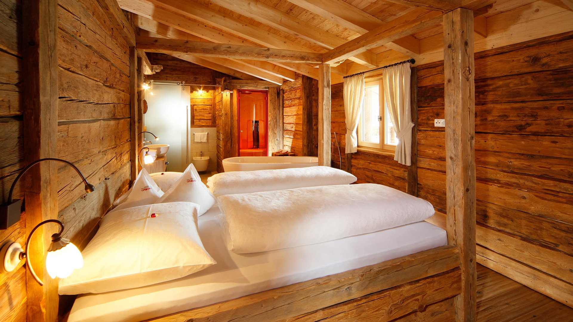Zimmer und Suiten Gemütliches Holzschlafzimmer mit weißer Bettwäsche und Badewanne im Hintergrund