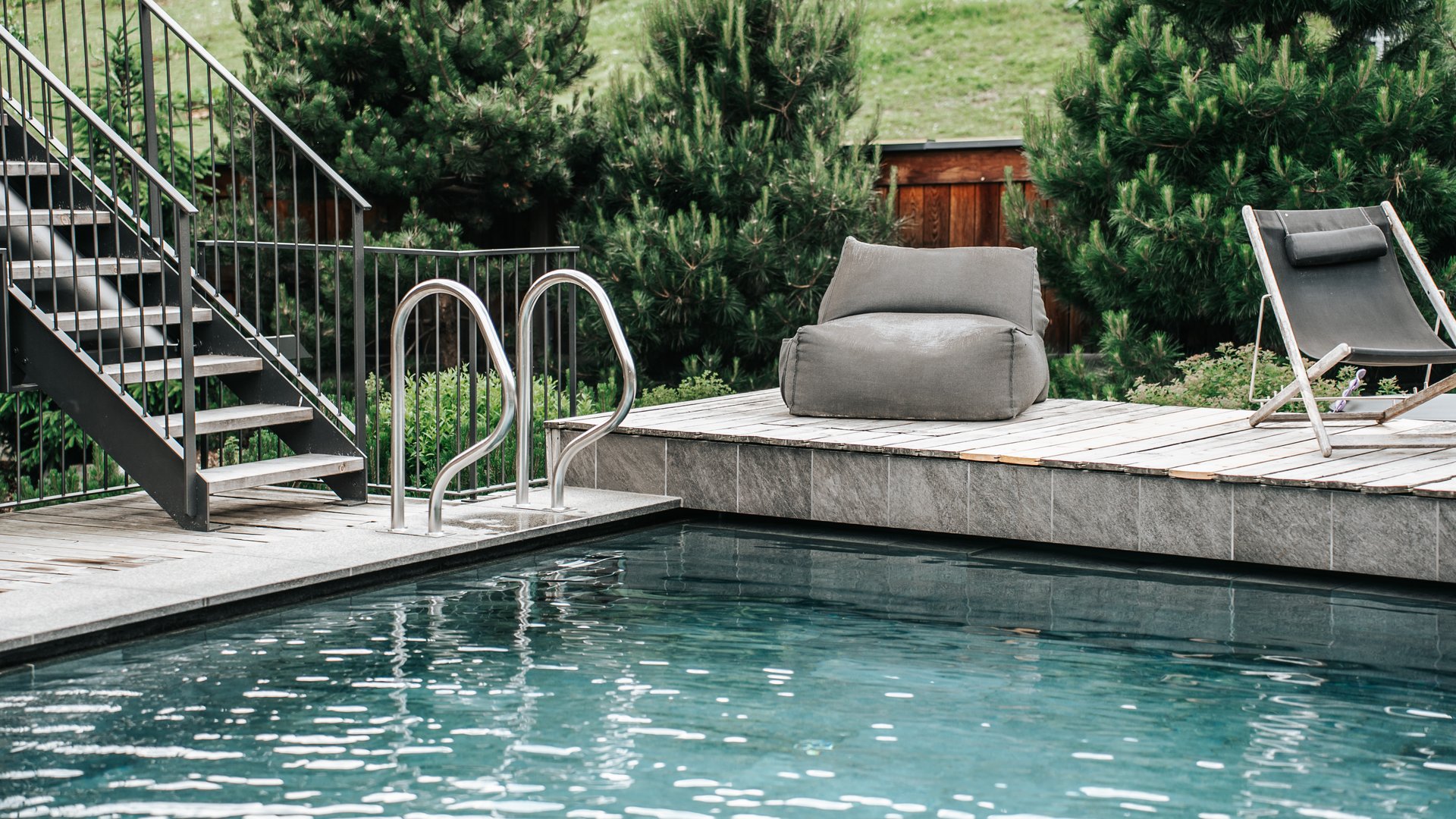 Our water world Modern outdoor pool with stairs, lounge chair, and bean bag on wooden deck