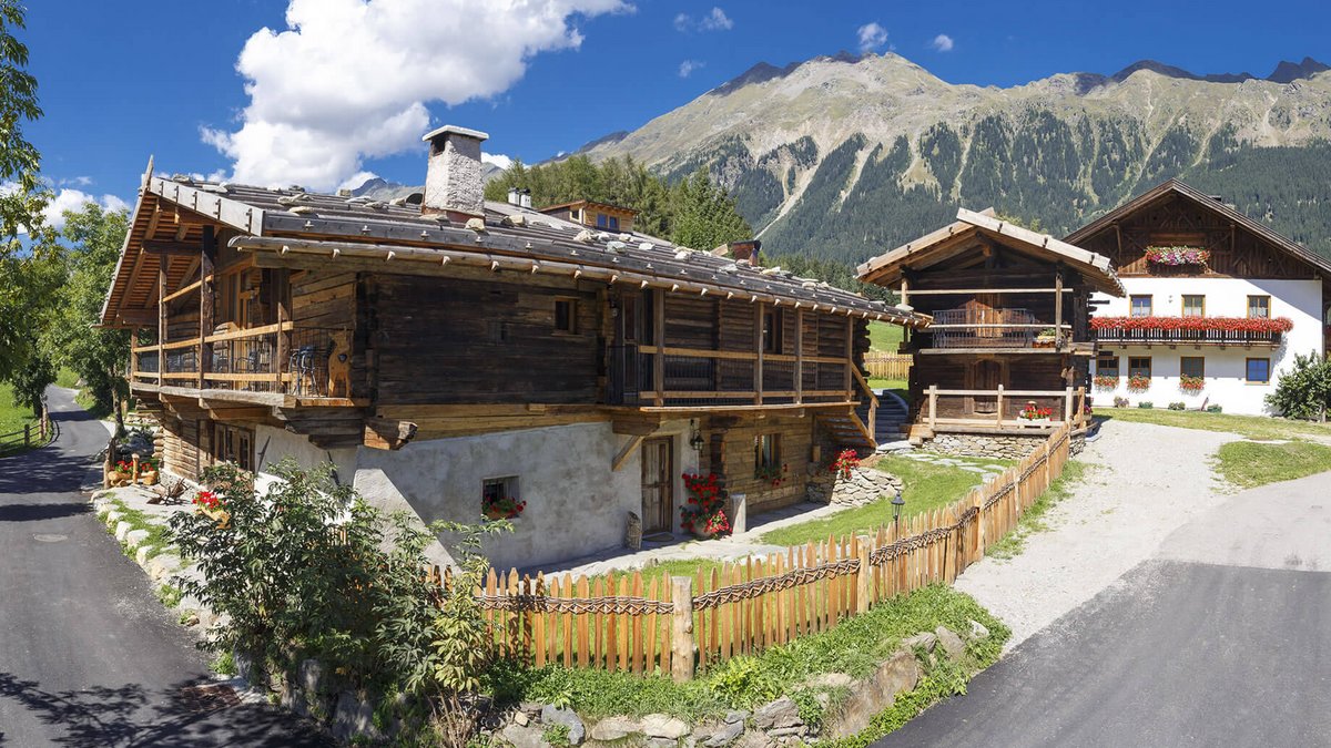 The historical Chalet Gratznhäusl Mountain cabins with flowers and mountain background under clear sky