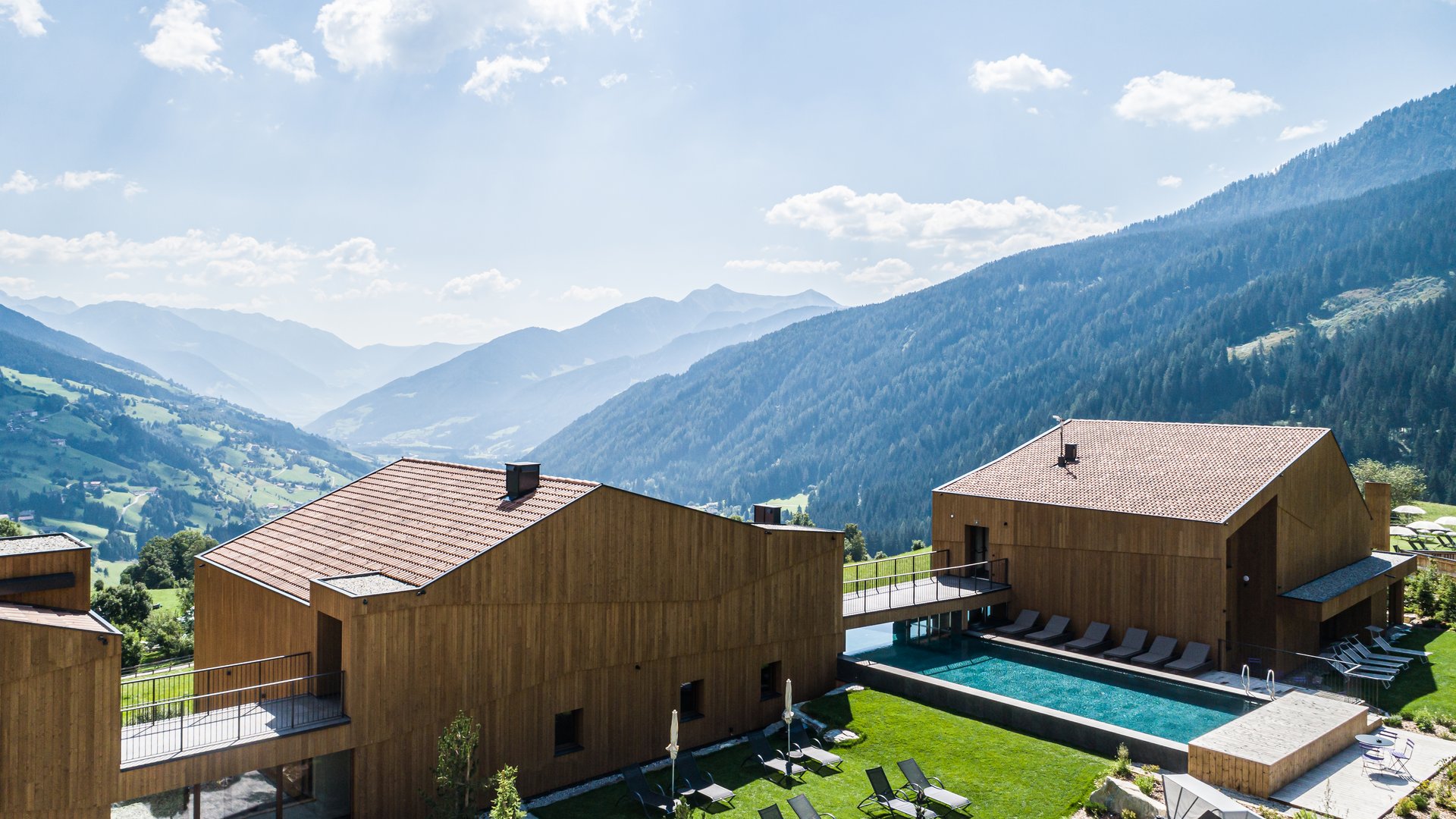 L’area wellness riservata agli adulti Edifici in legno con piscina e lettini in un paesaggio alpino