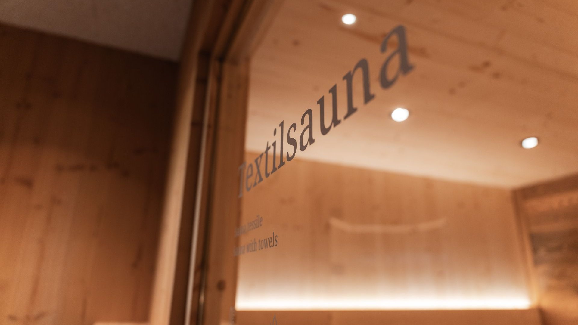 Gassenbadl: l’area wellness per famiglie Cartello della sauna su una porta a vetri in un ambiente rivestito in legno