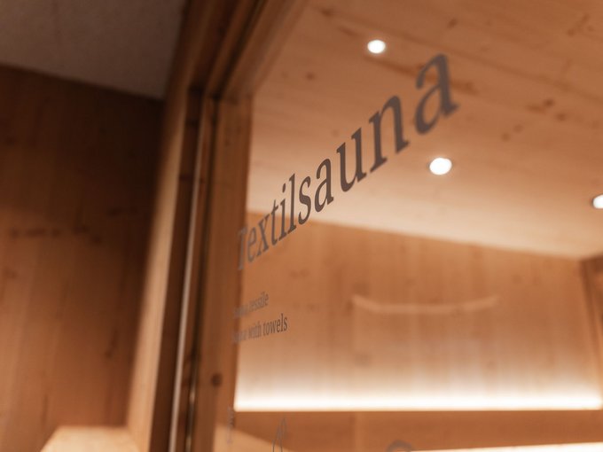 Familienurlaub im Gassenhof Sauna-Schild an einer Glastür in einem holzverkleideten Raum