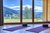 Yoga-Matten in Raum mit Blick auf Berglandschaft durch große Fenster