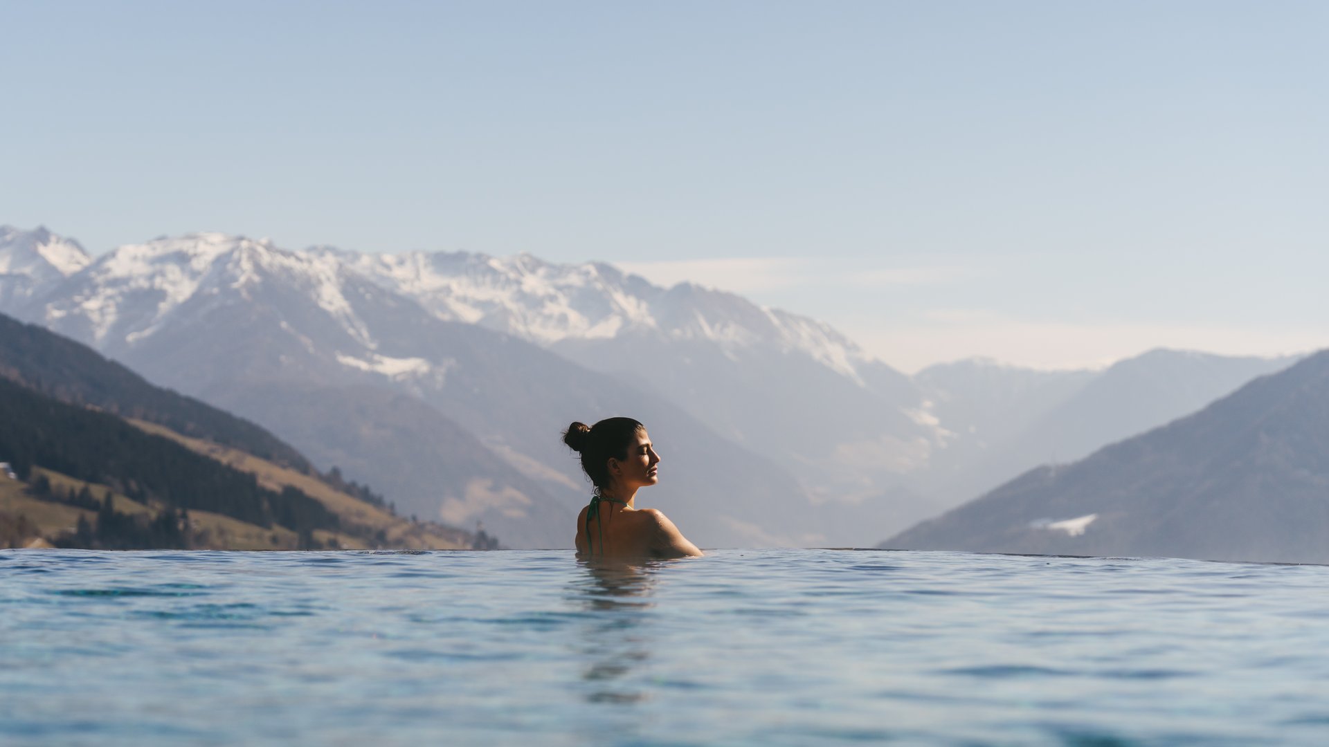Frau entspannt im Pool mit Blick auf verschneite Berge