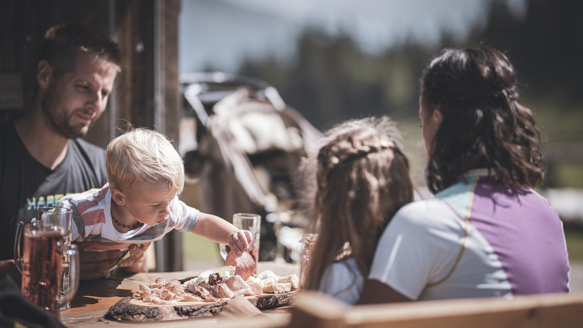 A place of experiences Family dining outdoors as a child reaches for food at the table