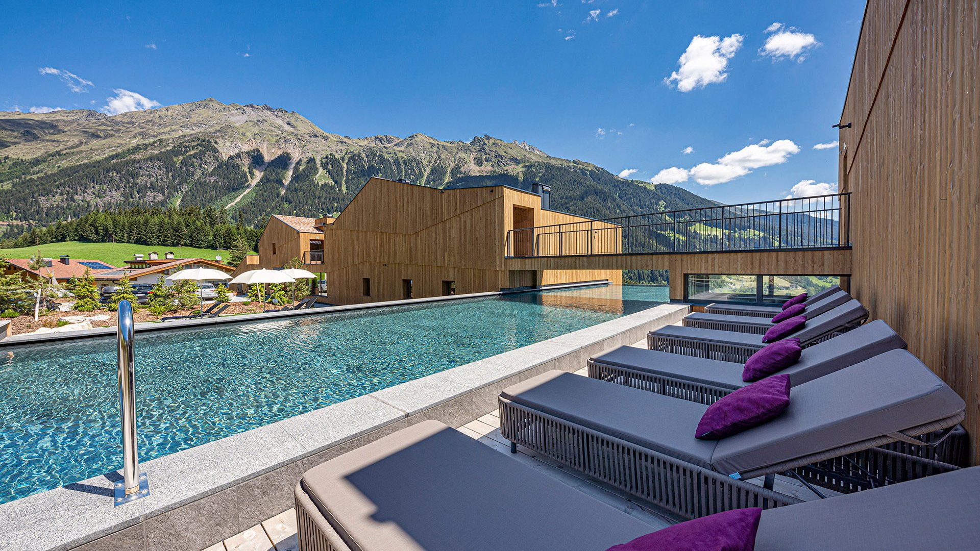 The best spot in the Ridnauntal valley Outdoor pool with lounge chairs and mountains in the background under clear sky