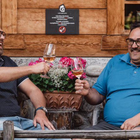 Neuigkeiten Zwei Männer stoßen mit Weingläsern im Freien an