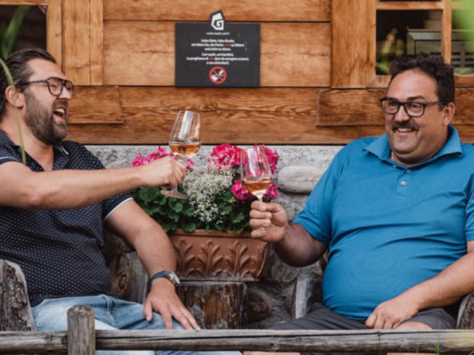 Durstkurort Gassenhof Zwei Männer stoßen mit Weingläsern im Freien an