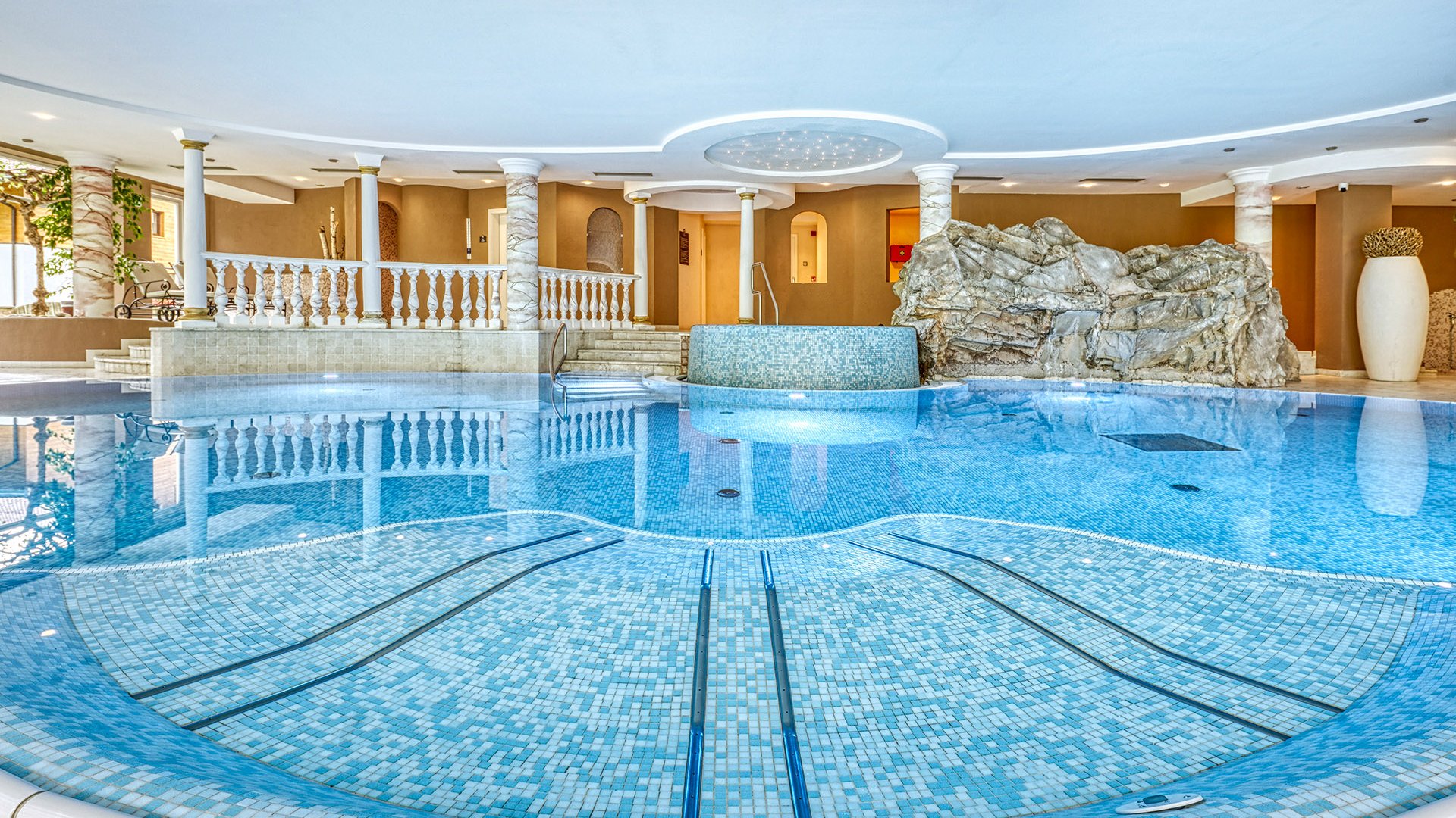 Hotel a Racines con centro benessere Vista interna di una piscina di lusso con piastrelle a mosaico e colonne