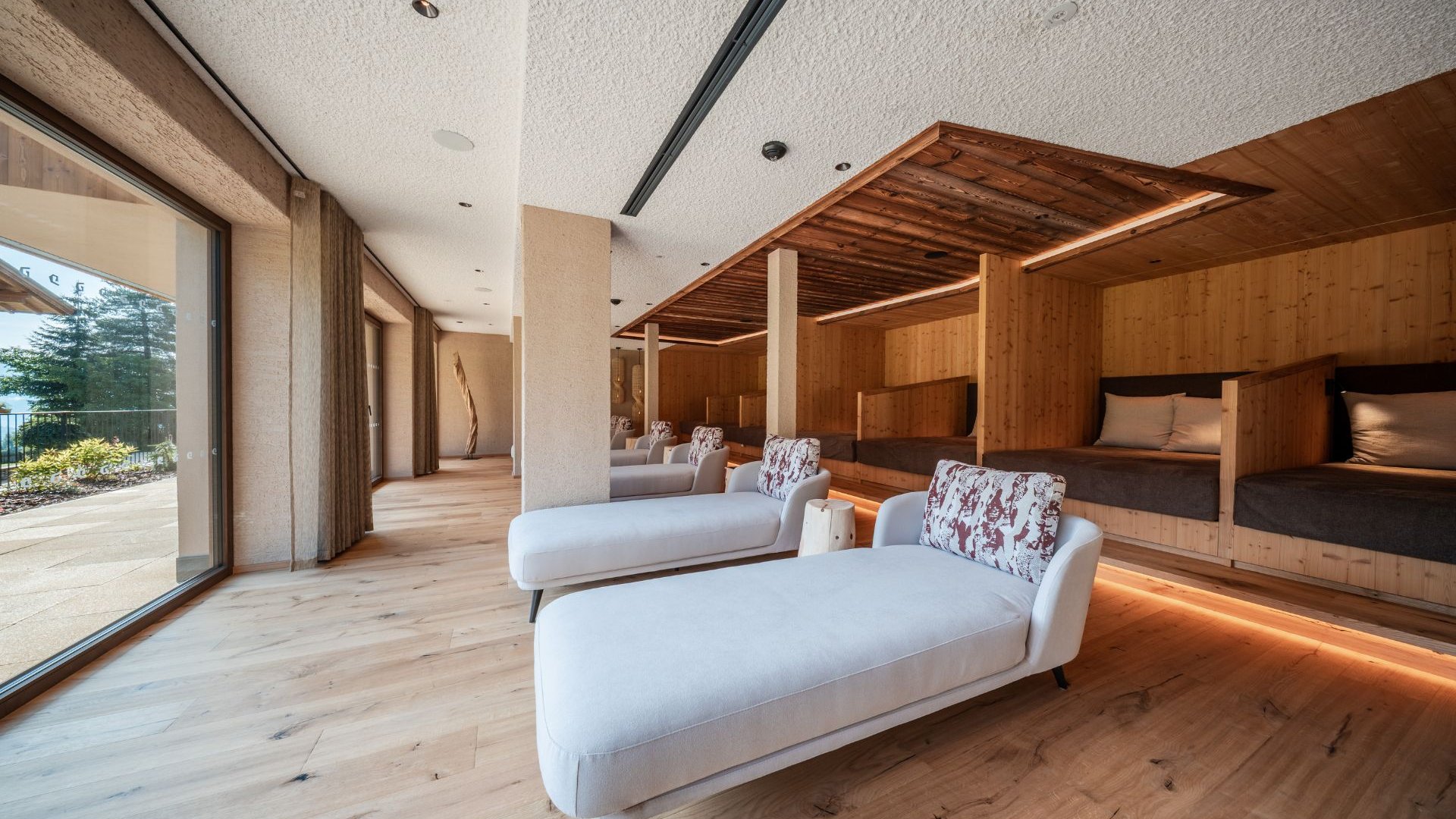 Gassenbadl: l’area wellness per famiglie Sala relax luminosa con chaise longue bianche e nicchie in legno