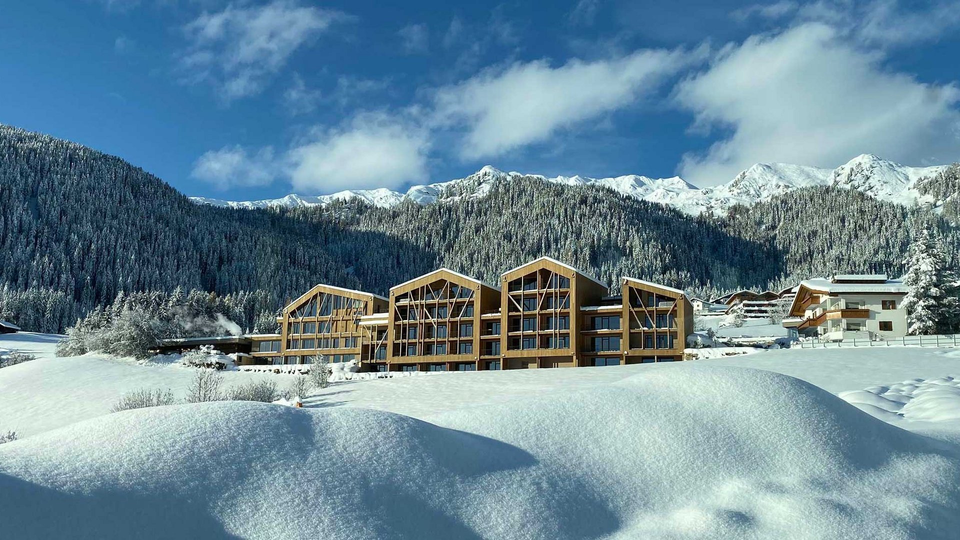 Winterlandschaft mit schneebedeckten Bergen und modernen Holzhäusern