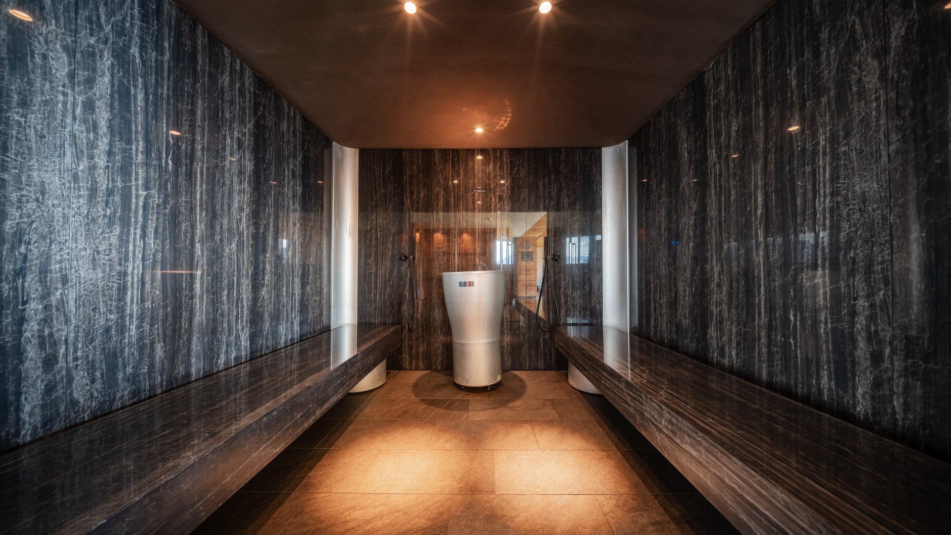 L’area wellness riservata agli adulti Elegante sala spa con pareti in pietra scura, panche e lavabo bianco