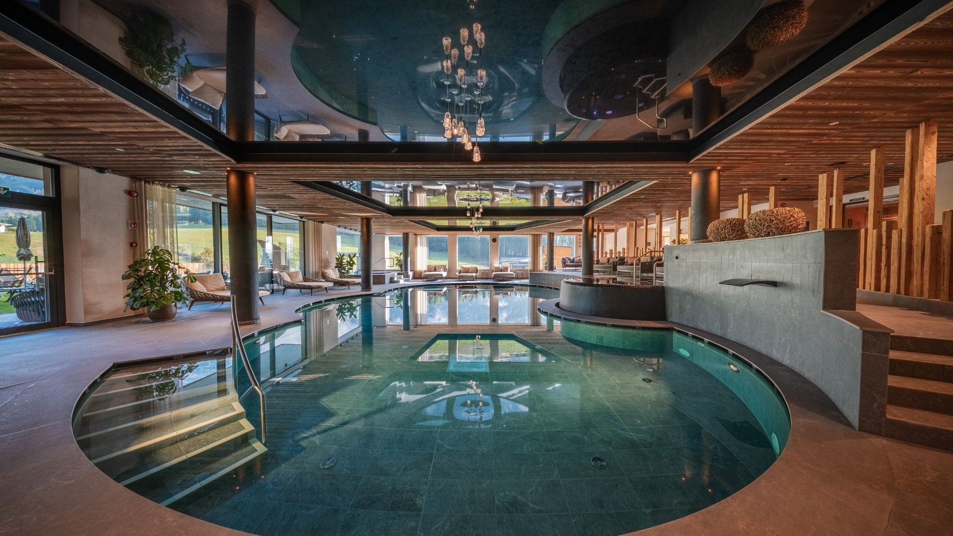 Gassenbadl: l’area wellness per famiglie Elegante piscina interna con aree relax, soffitto in legno e lampadario